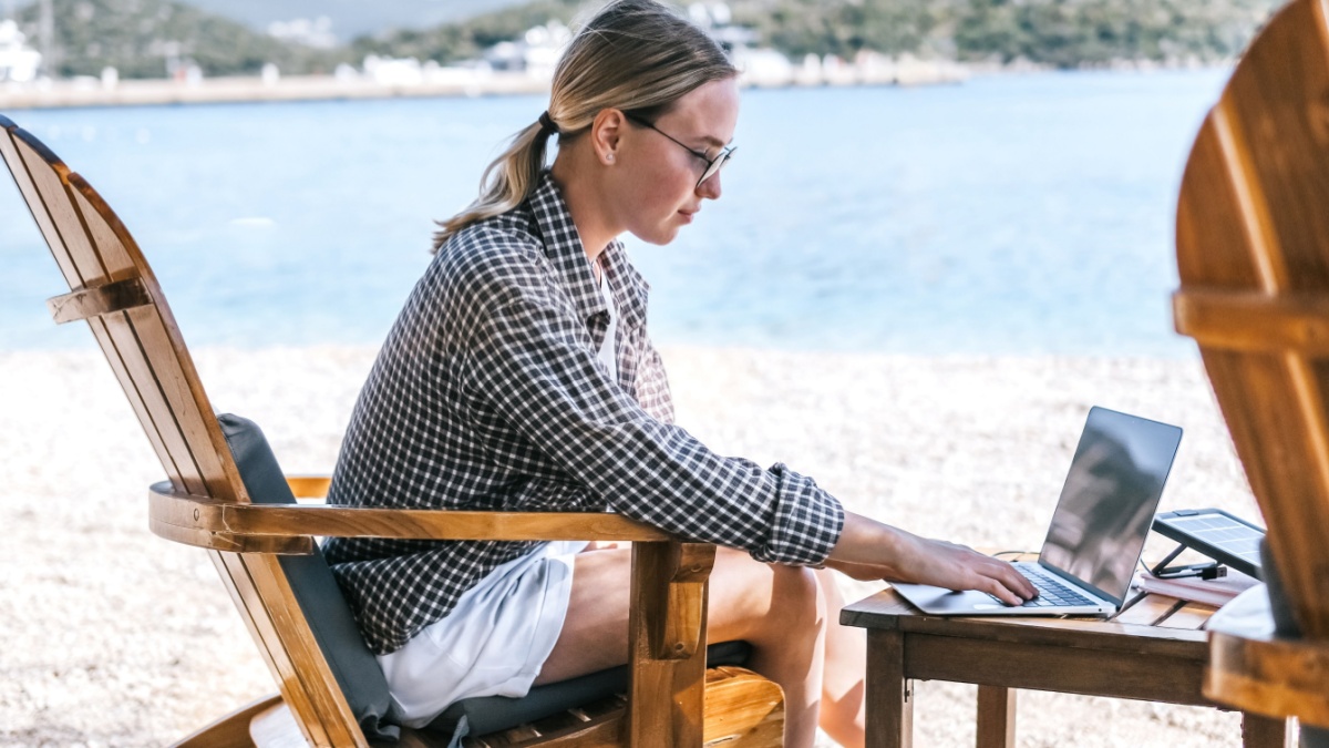 Ragazza al mare con computer portatile